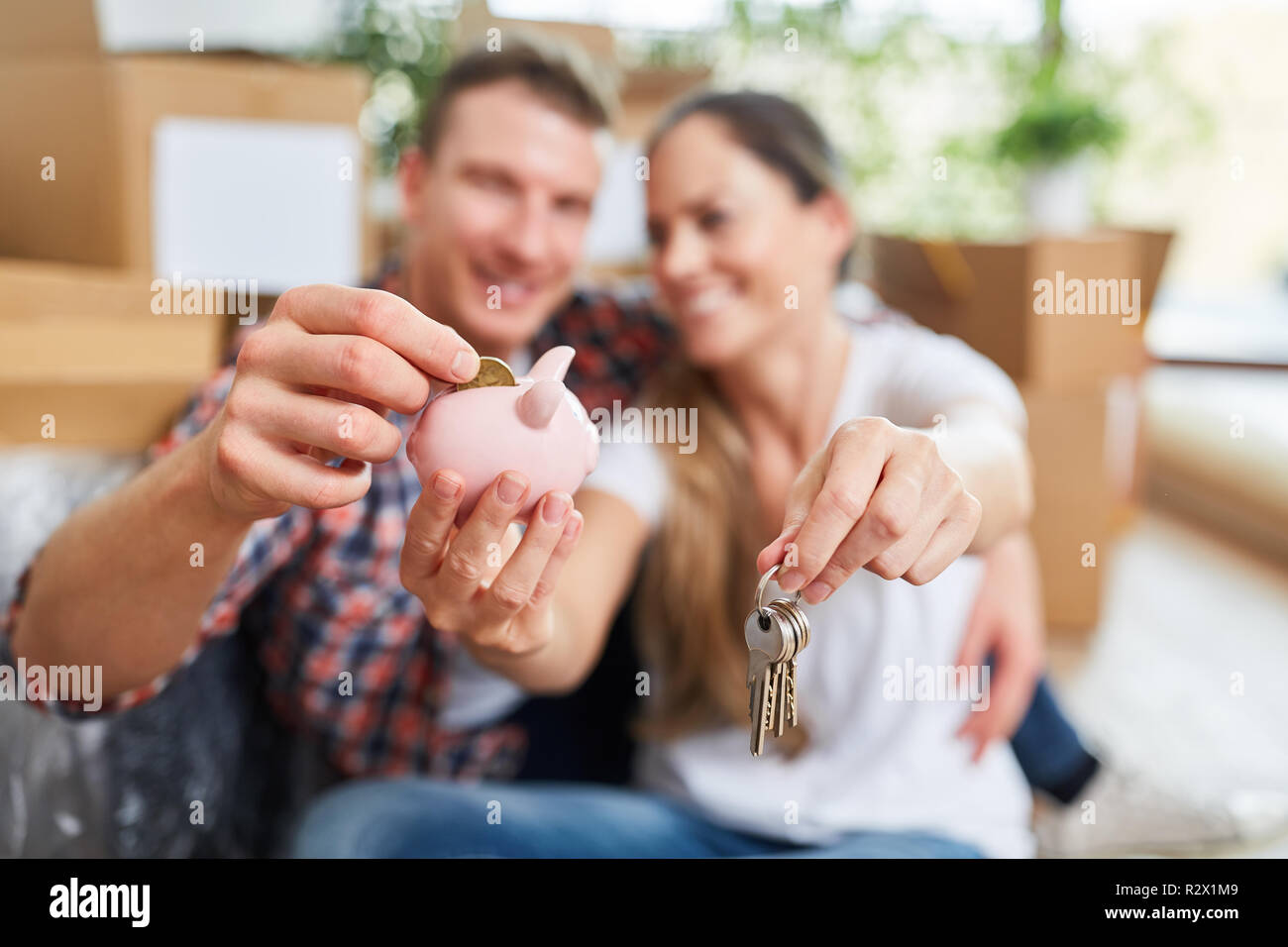 Happy couple in new home with piggy bank as symbol for finance Stock Photo