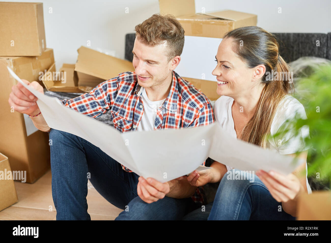 Young couple with blueprint planning home construction between moving boxes Stock Photo