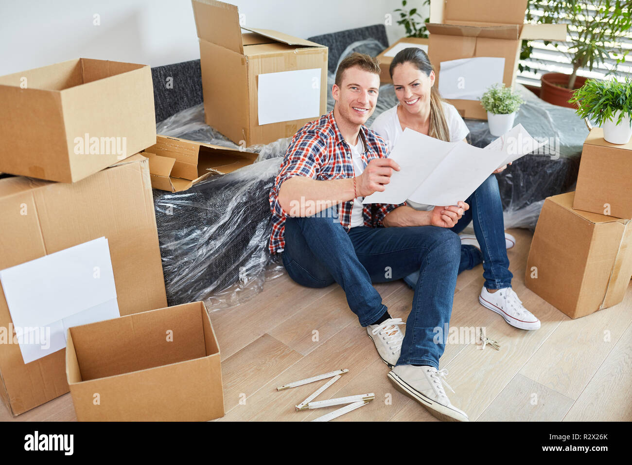 Young couple moving with blueprint looking forward to the new house as a home Stock Photo