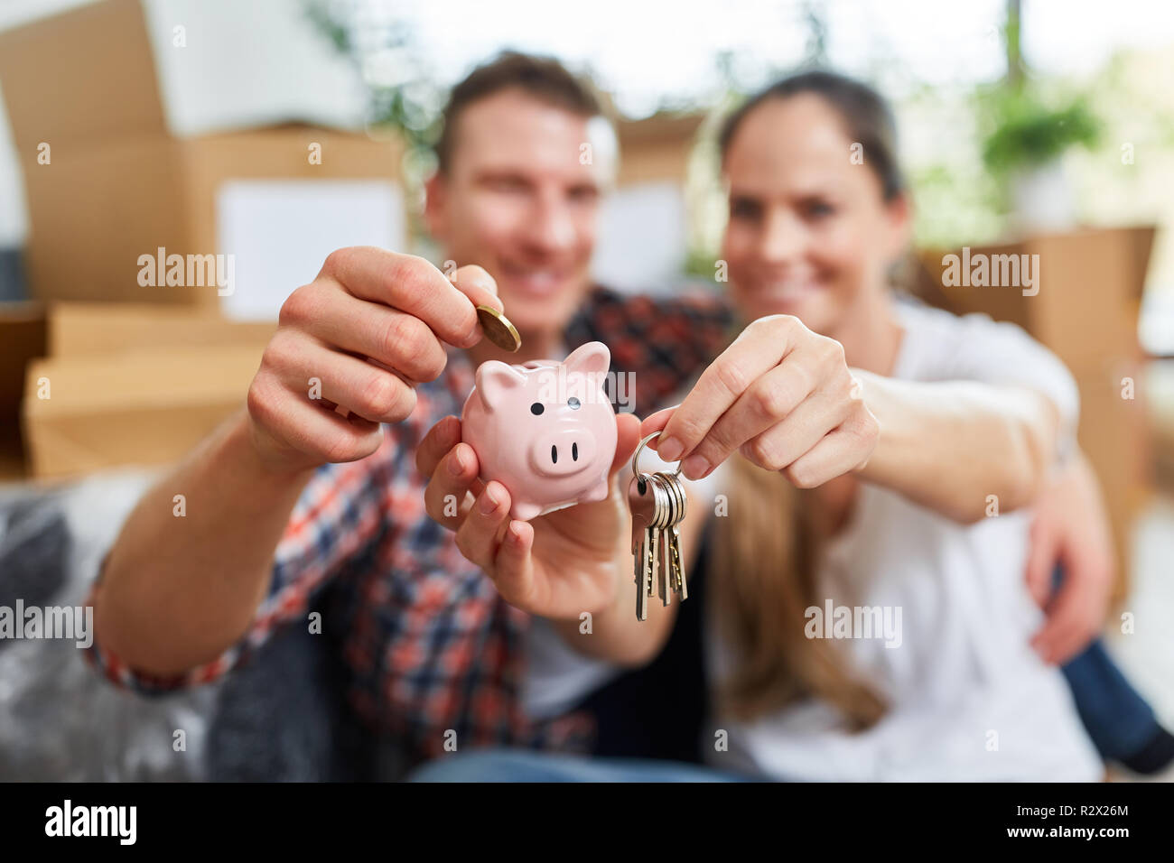 Happy couple with piggy bank and keys in new home as a home Stock Photo