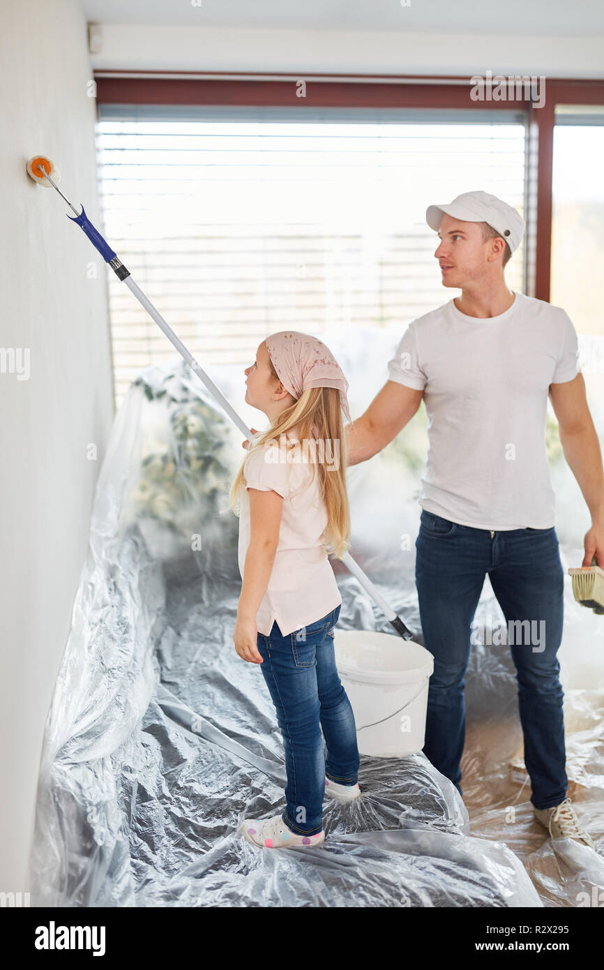 Father and daughter together paint a wall while renovating at home ...