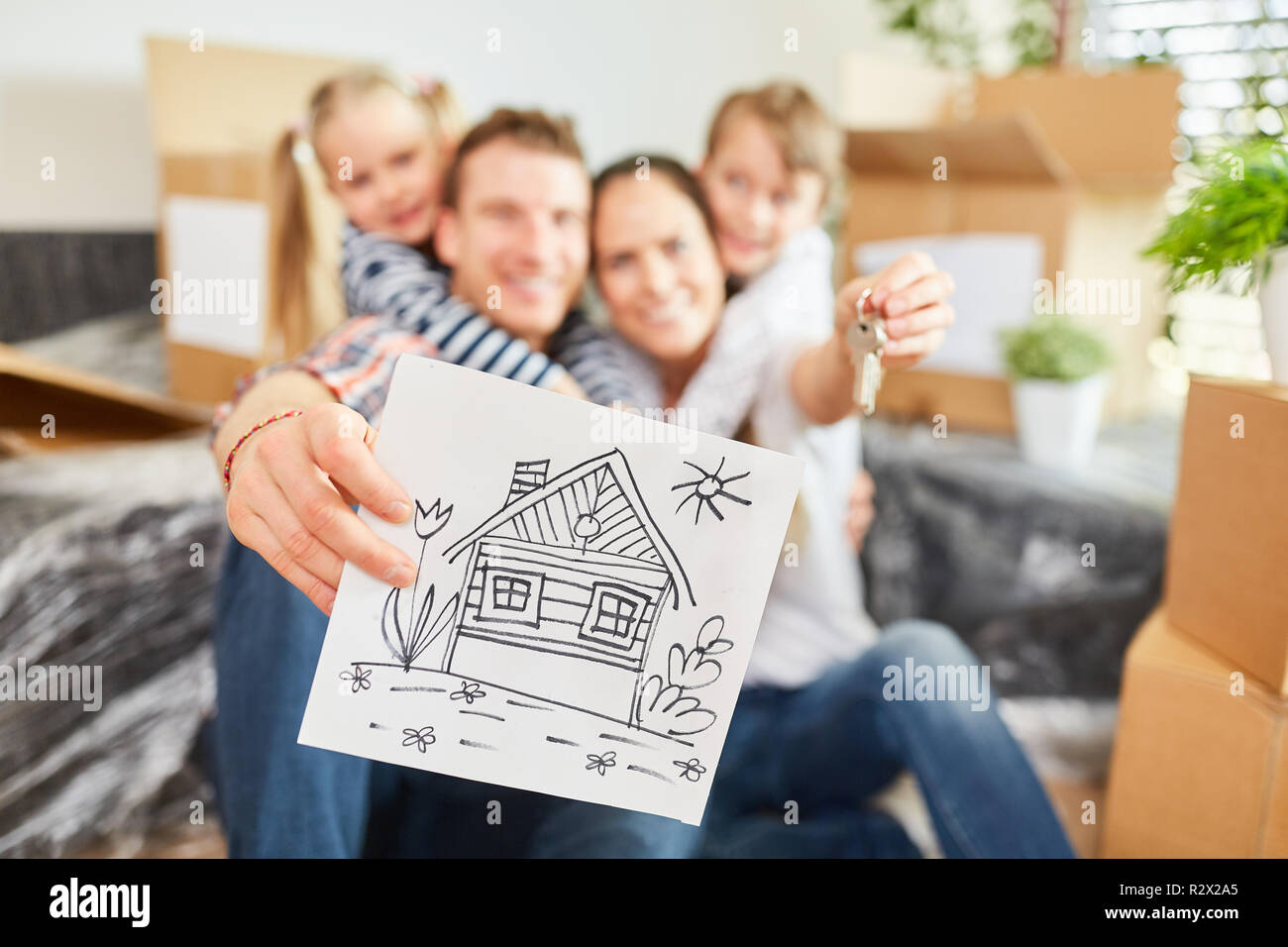Happy family with a key is holding a drawing of the new home Stock Photo