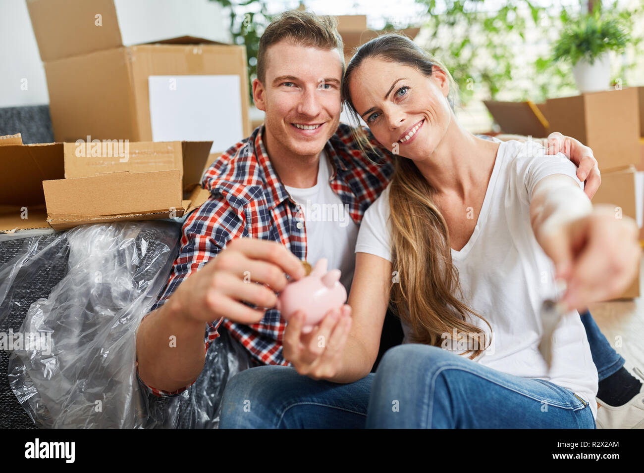 Happy couple after moving piggy bank in new home Stock Photo
