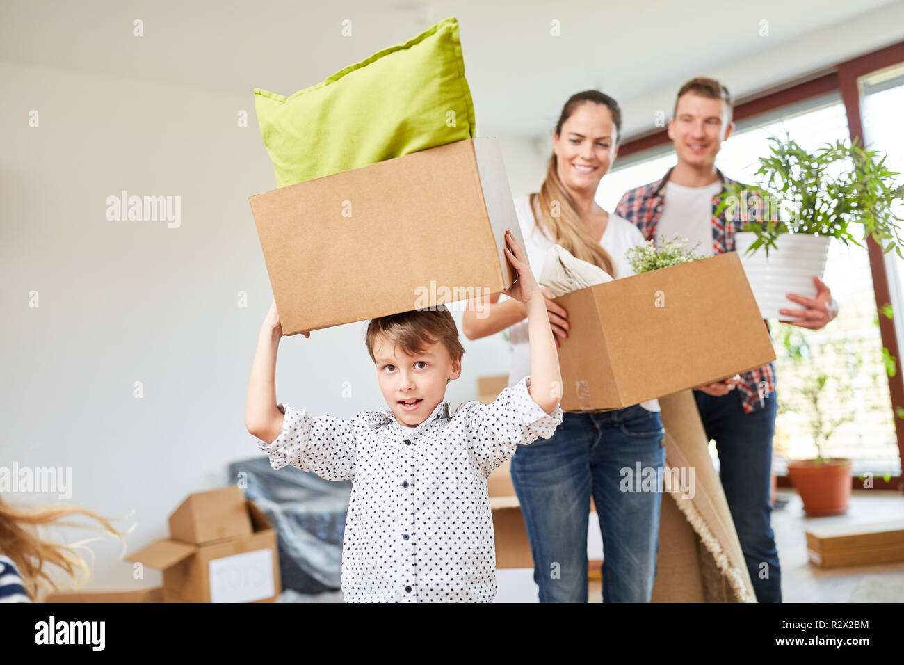 Little boy helps with the move and carries moving boxes in the new home