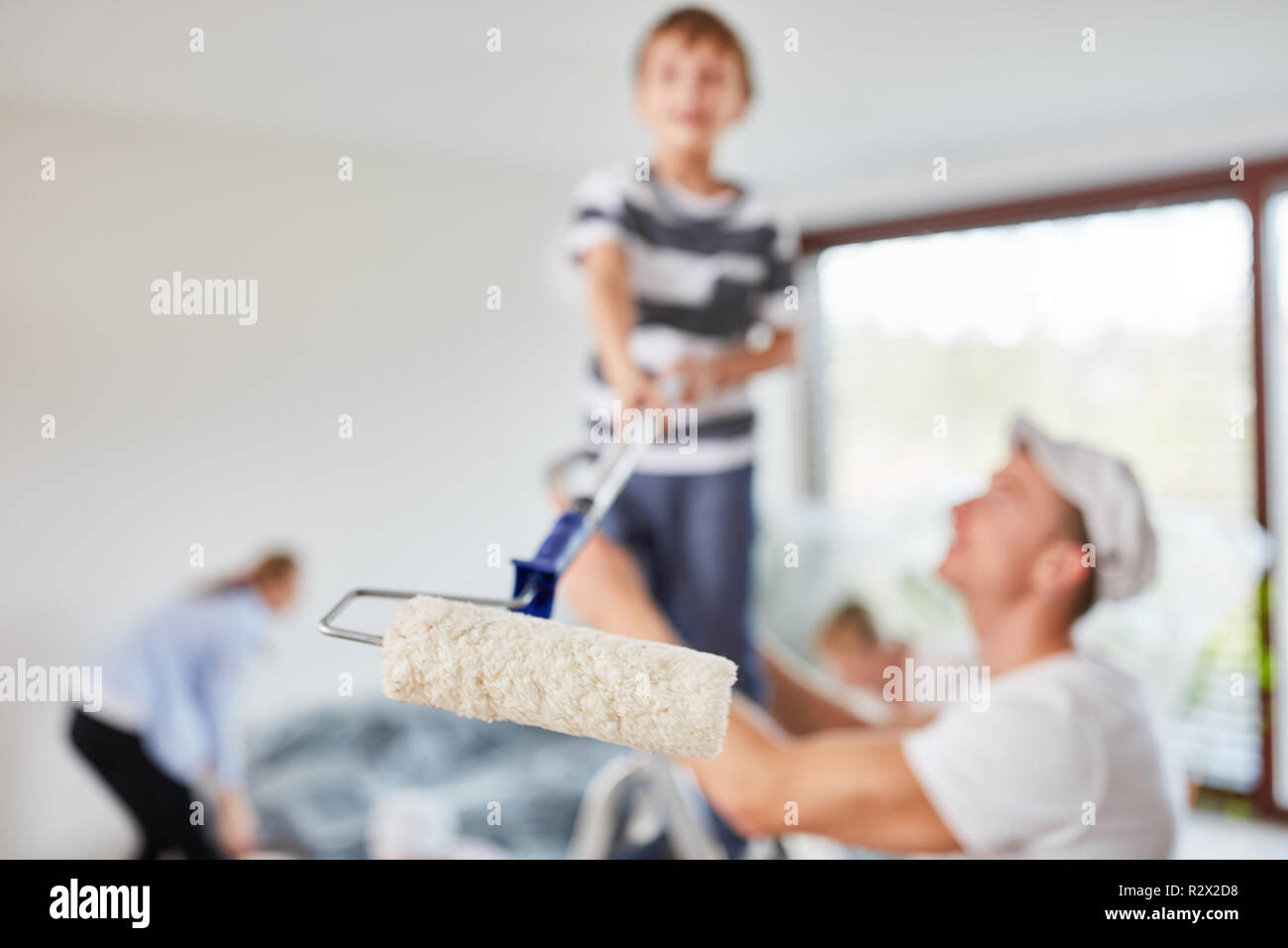 Child helps with renovating and painting with the paint roller before