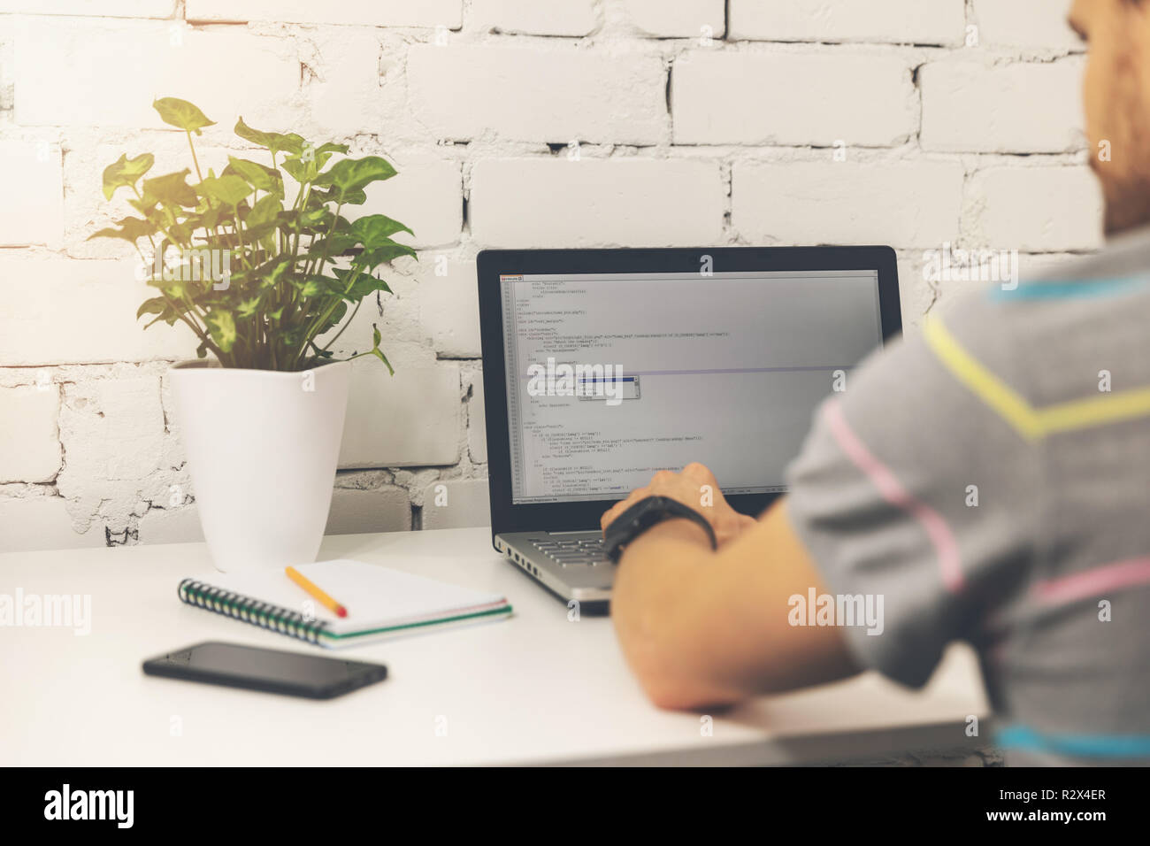 programmer writing programming code on laptop in bright office Stock Photo