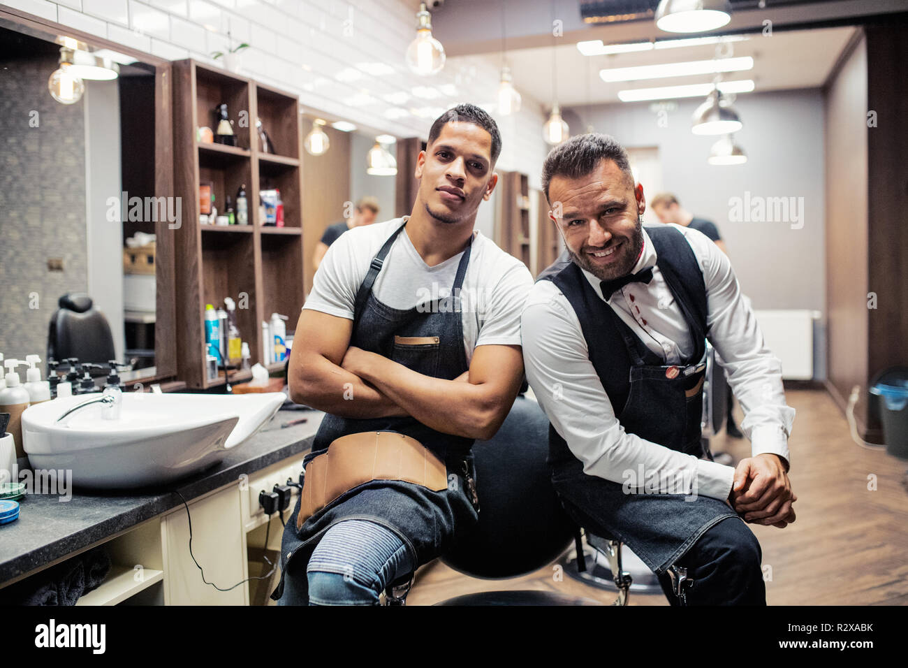 Two male haidressers and hairstylists sitting in barber shop. Stock Photo
