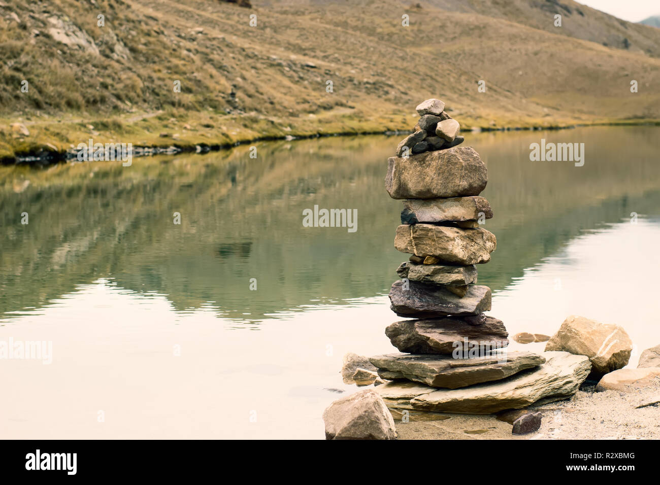 Stone balance with the background of a high mountain lake in Himachal Stock Photo