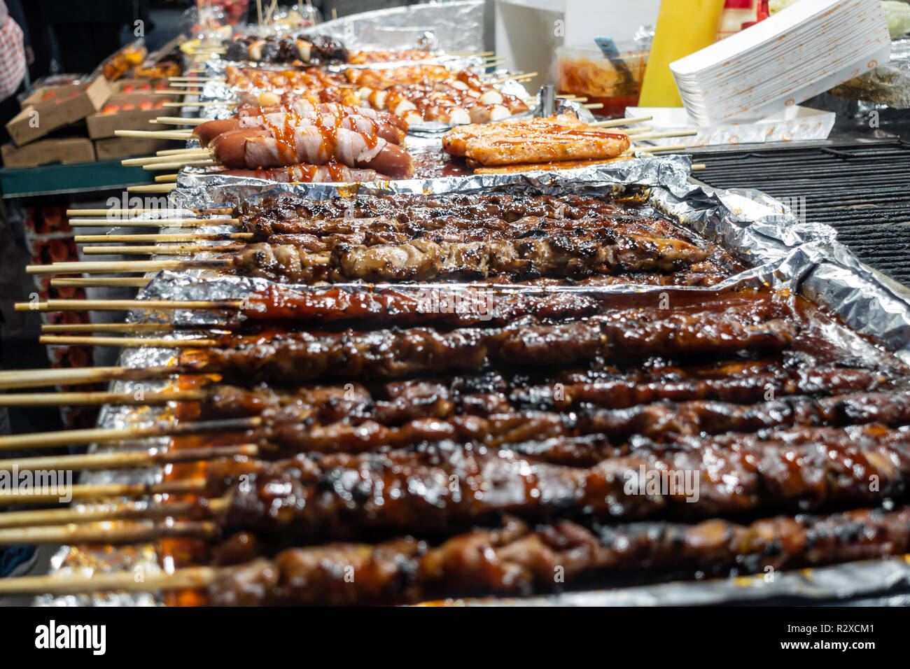 Grilled pork kebab and sausages on wooden skewers on sale at a street
