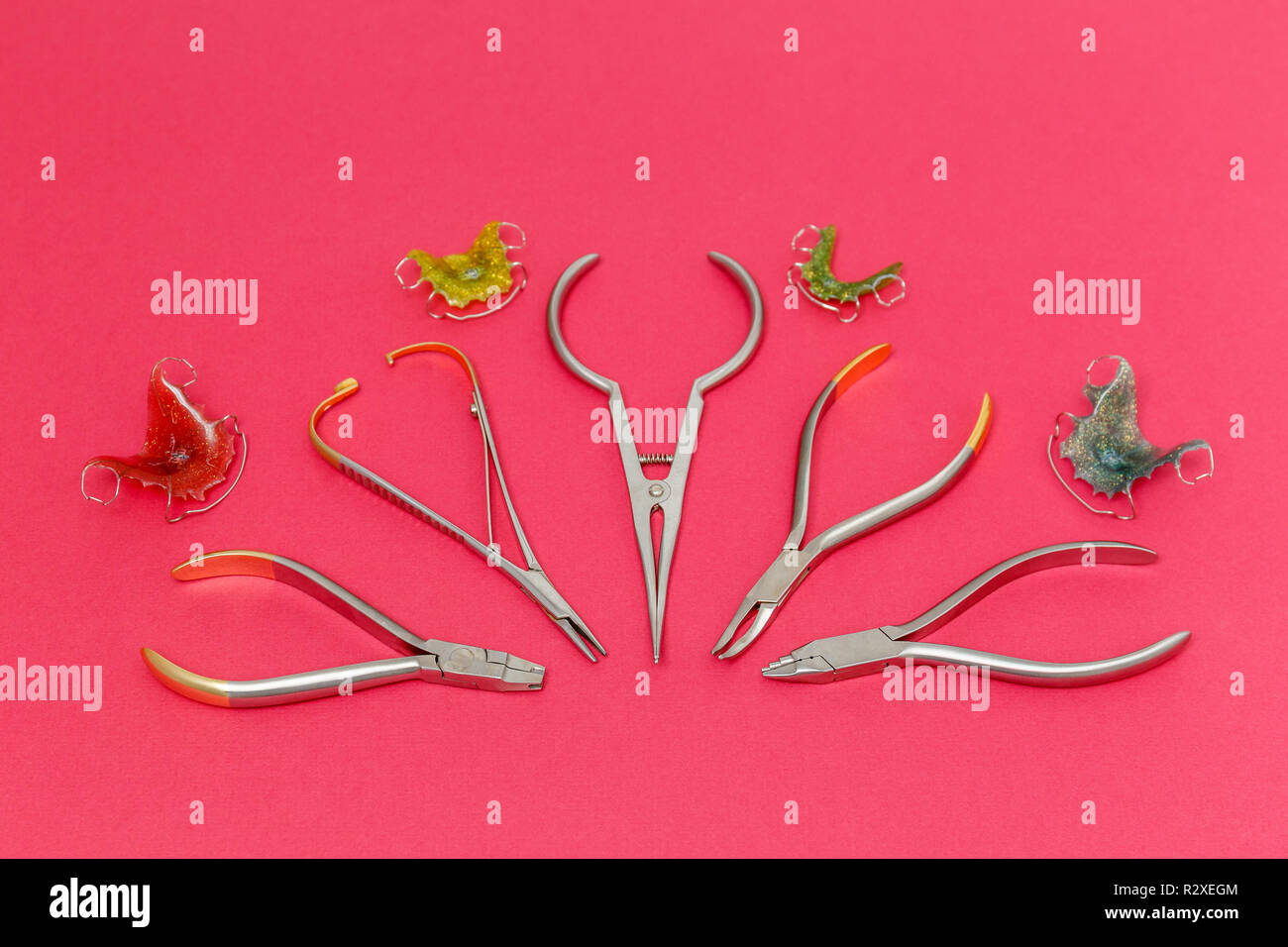 Orthodontic medical metal tools and dental braces or retainers on pink