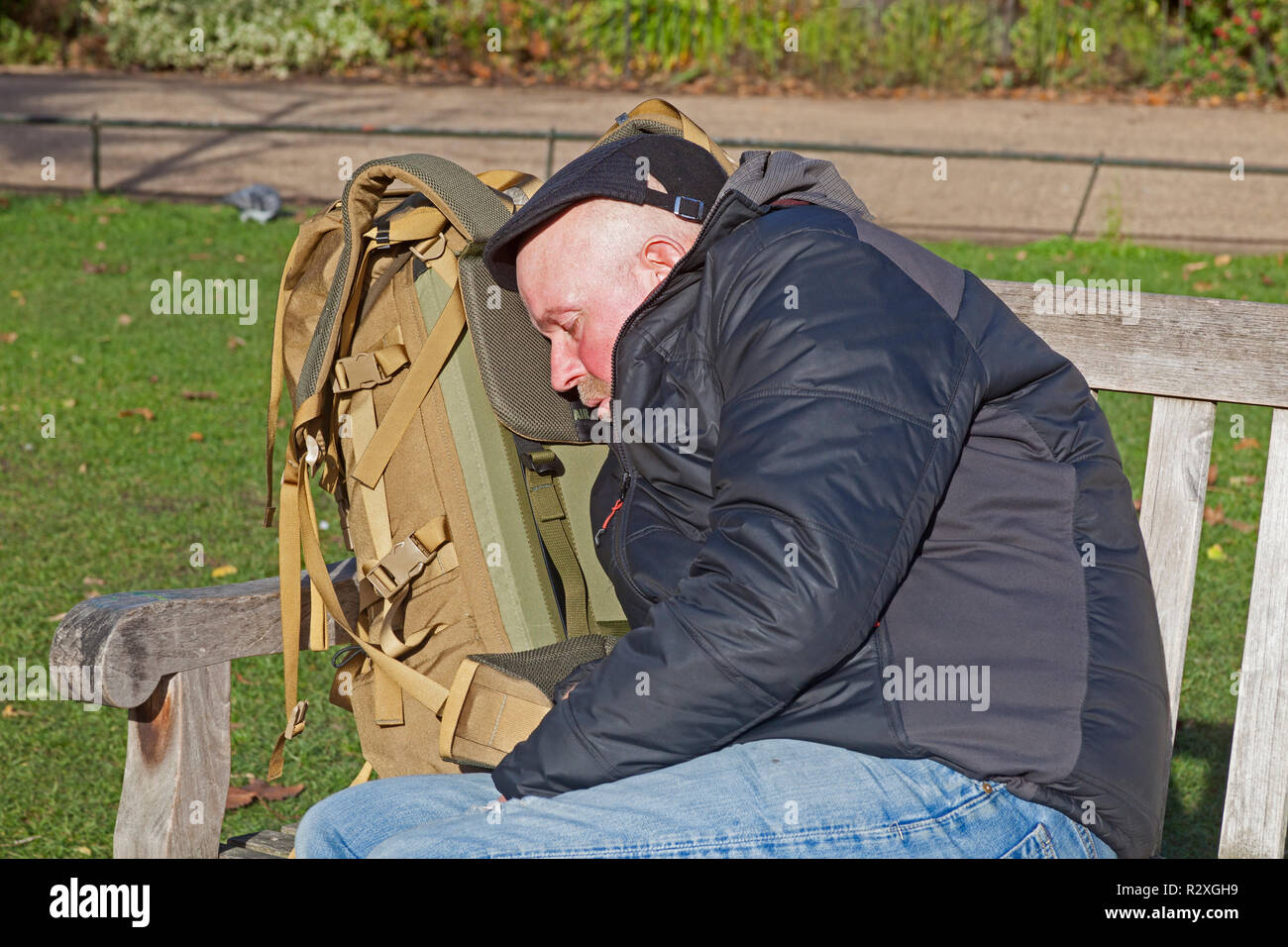 London, Westminster.  A weary traveller using his rucksack to rest his head on a bench in St James's Park. Stock Photo