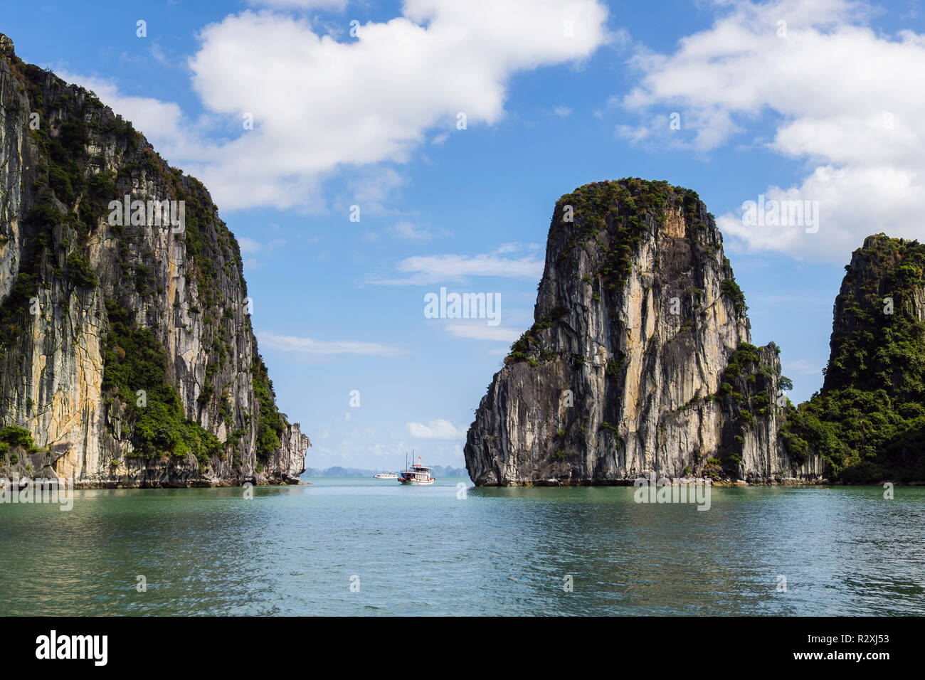 A Tourists junk boat sails between steep sided limestone rock islands in Halong Bay in South China Sea. Ha Long, Quảng Ninh, Vietnam, Asia Stock Photo