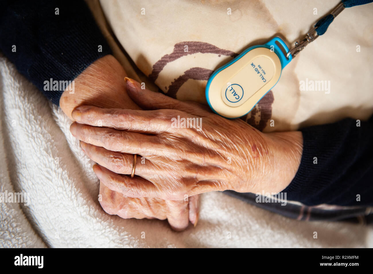 Old lady's hands showing age, alarm button and gold wedding band. Stock Photo
