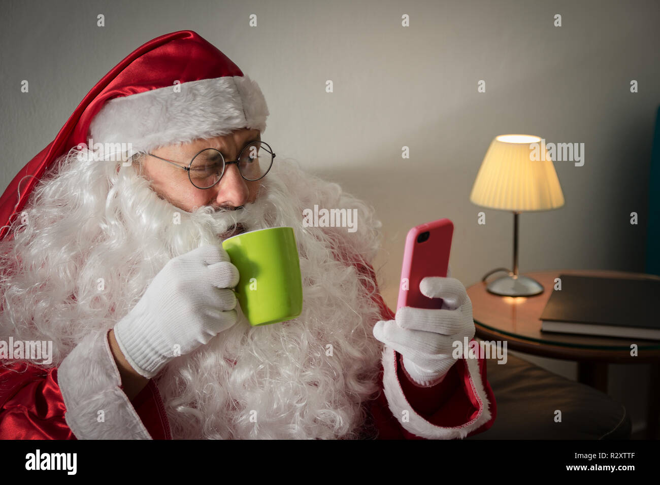 Half profile of Santa Claus or Father Christmas relaxing in couch in the living room Using wireless device online. Looking at cell phone screen and Stock Photo Alamy