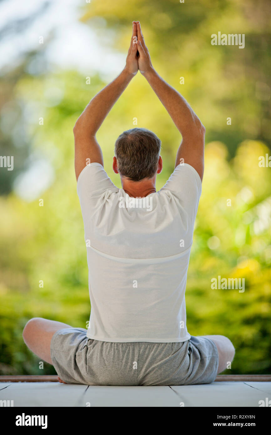 Relaxed middle aged man meditating on a deck. Stock Photo