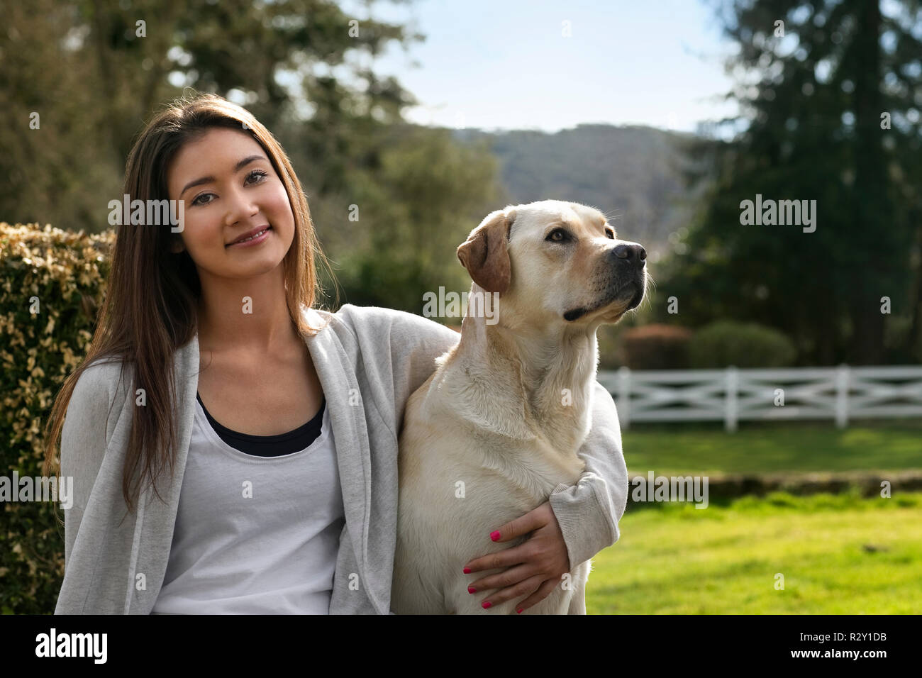 Portrait of a happy young woman relaxing in the garden with her dog. Stock Photo
