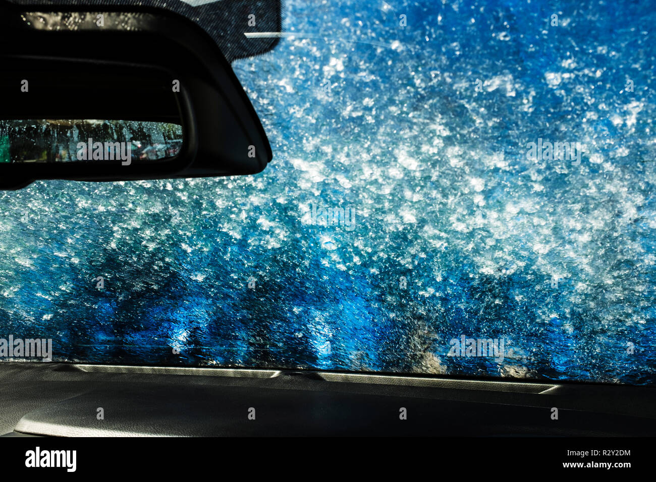 View from the inside of a car in an automated car wash, blue washers and soapy water over the