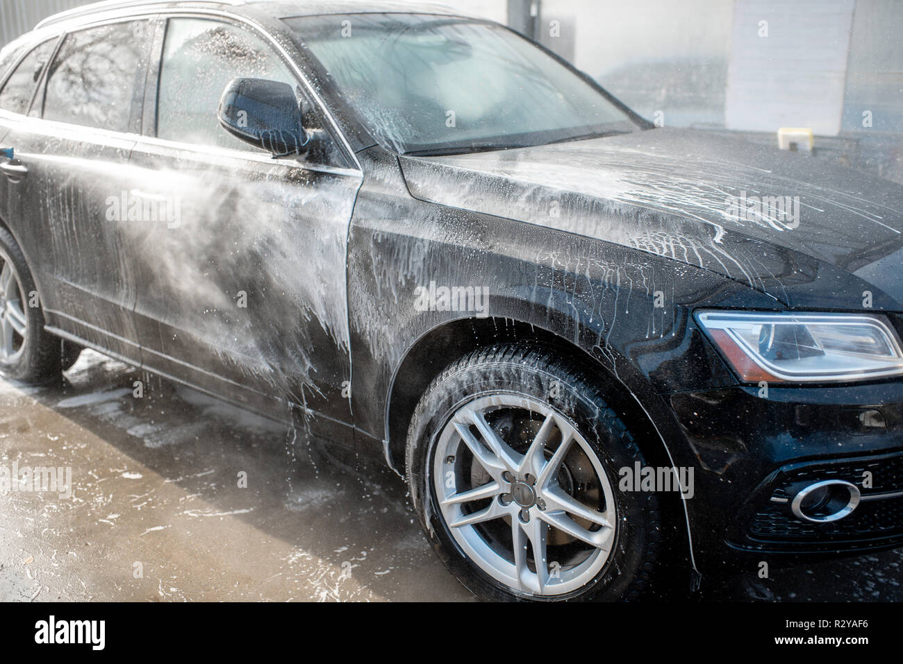 Closeup of a car under the water jet during the washing process on a