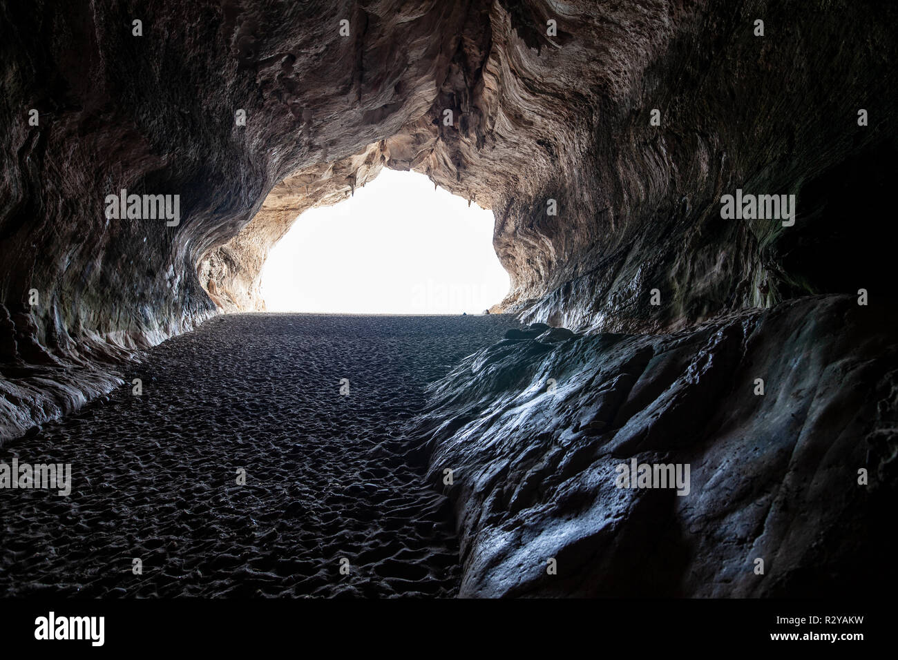 Sea cave on Cala Luna sandy beach in Sardinia, Italy. Light at the end of cave Stock Photo