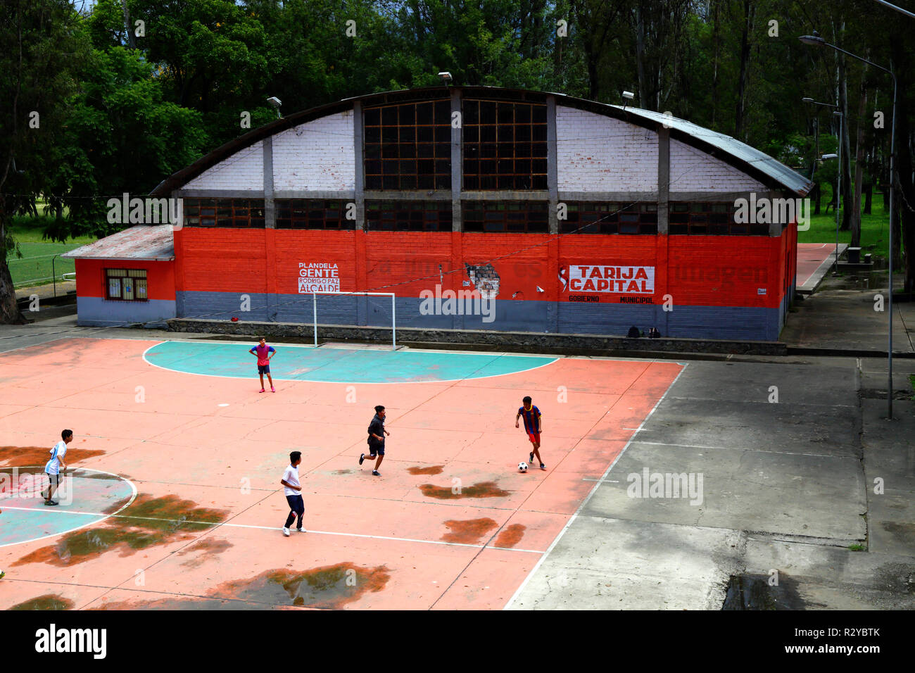 Youths playing football on outdoor concrete pitch in sports centre, Tarija, Bolivia Stock Photo