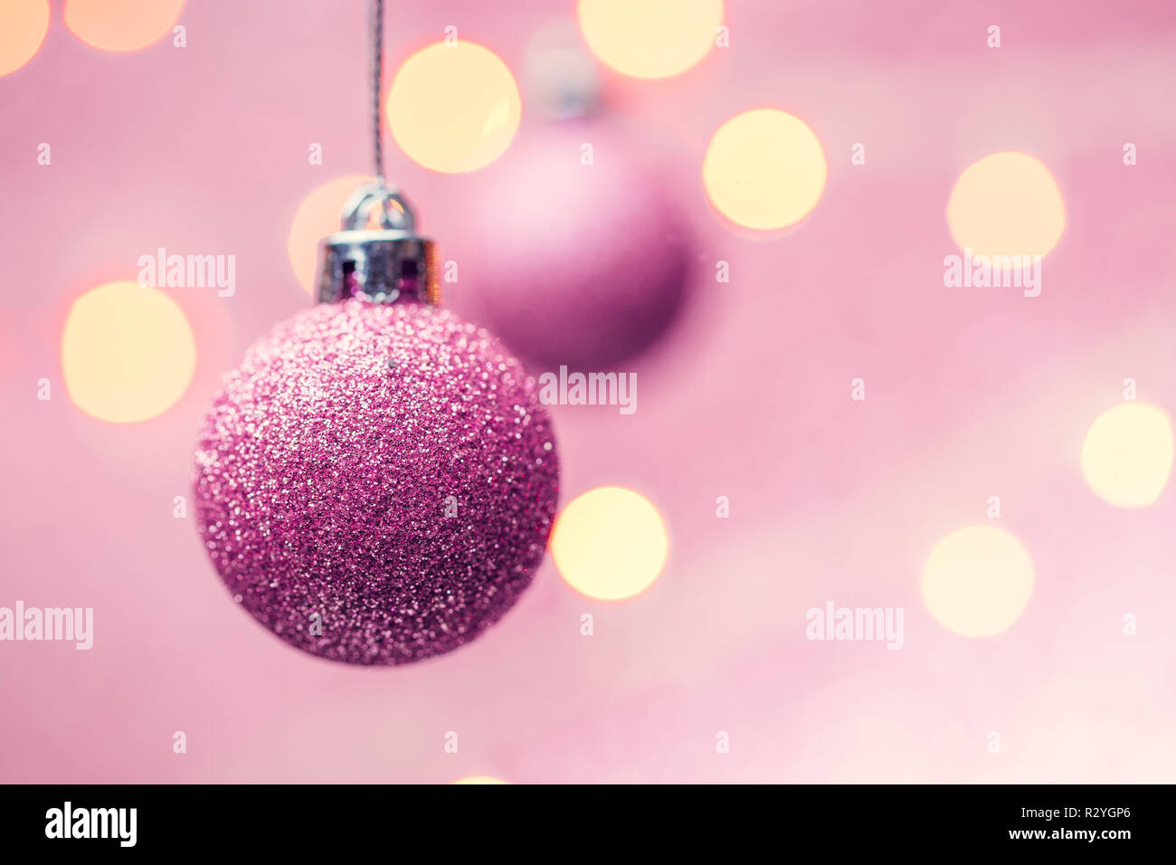 Photo of two New Year's pink balls on pink background with spots. Place for text Stock Photo