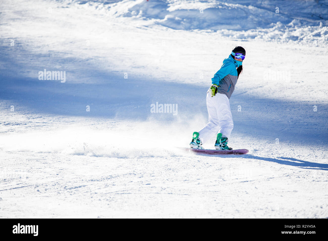 Photo of sports woman wearing helmet and mask snowboarding on snowy slope Stock Photo