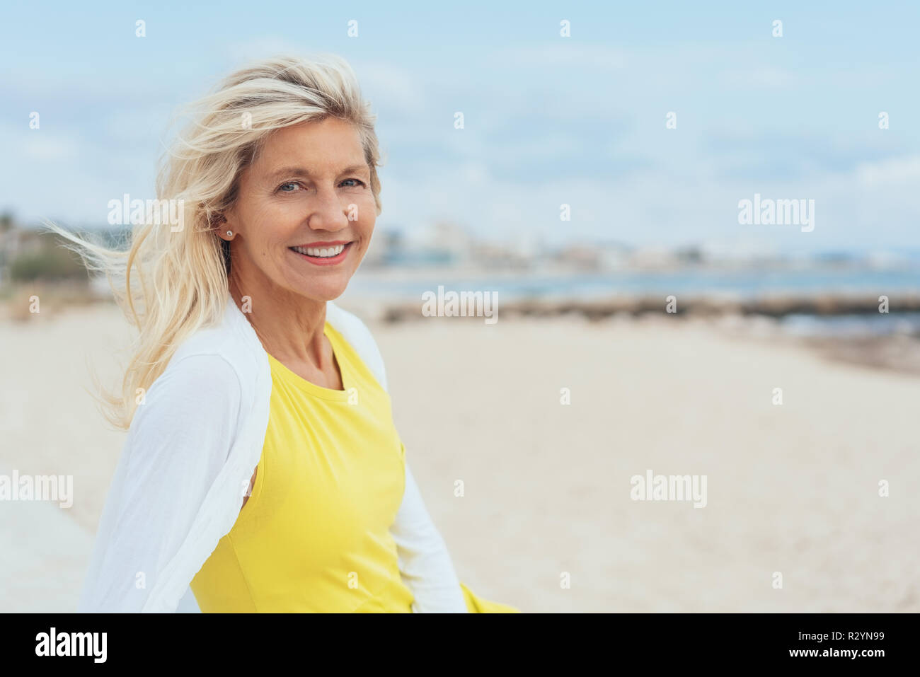 Attractive Woman With Tousled Hair On A Windy Beach Turning To