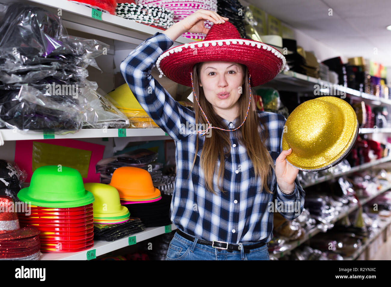 Smiling girl looking for funny hats in store of festival outfits and  accessories Stock Photo - Alamy