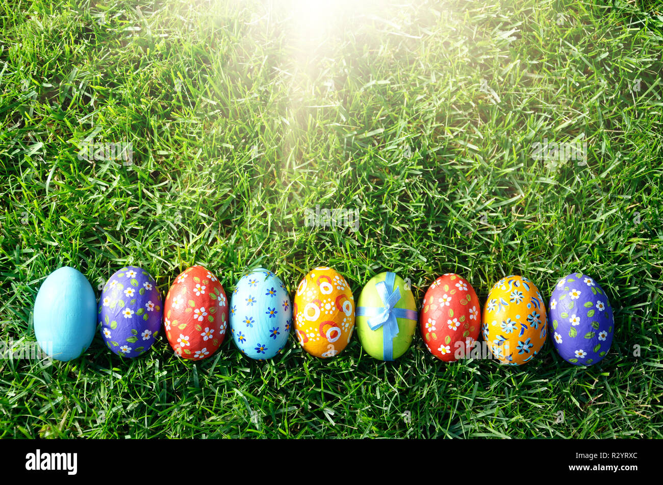 Easter eggs lying on green spring grass arranged in one lane. Space for ...