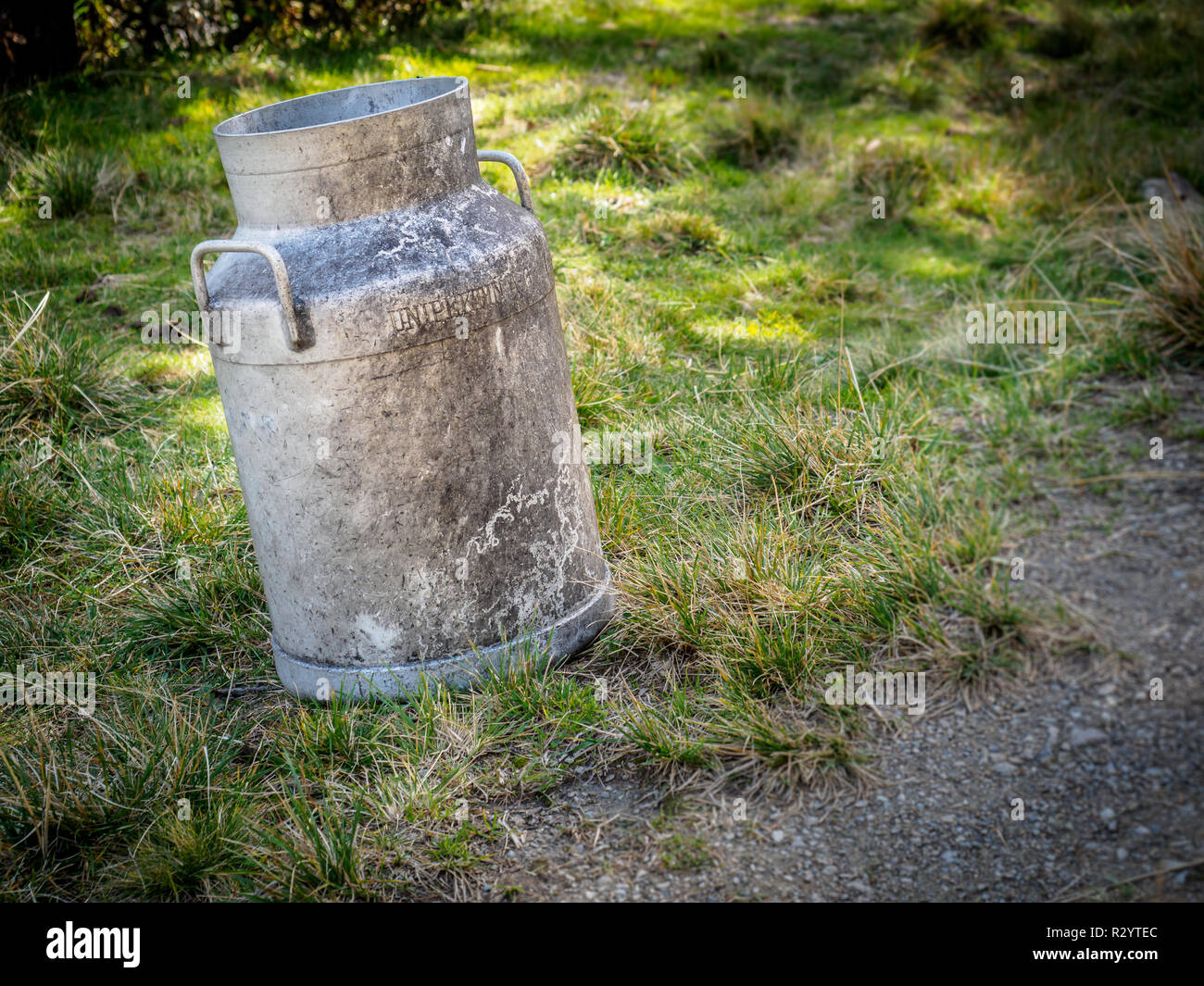 old milk can stands lonely on the side of the road Stock Photo