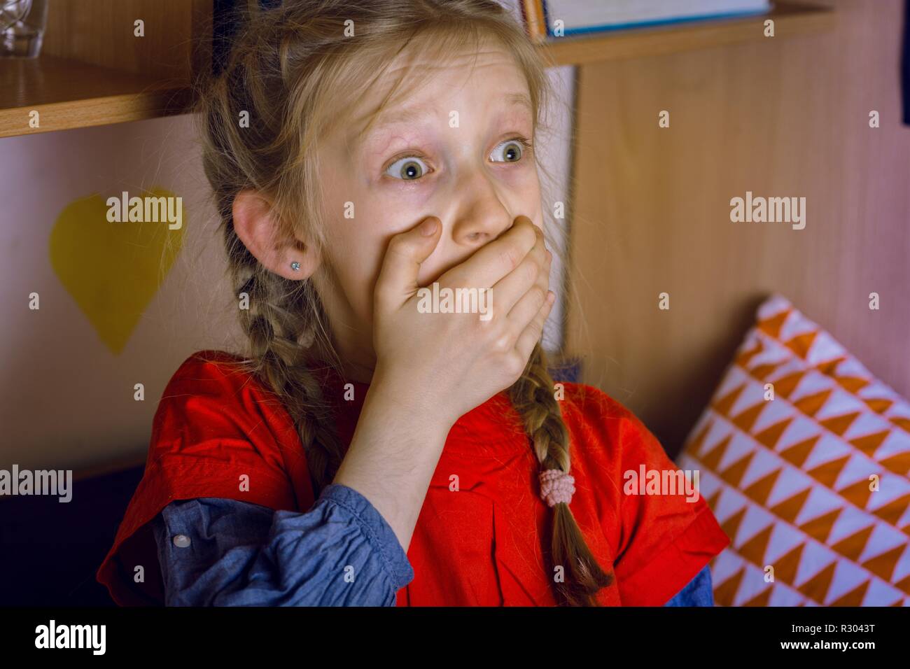 little girl is scared watching TV Stock Photo