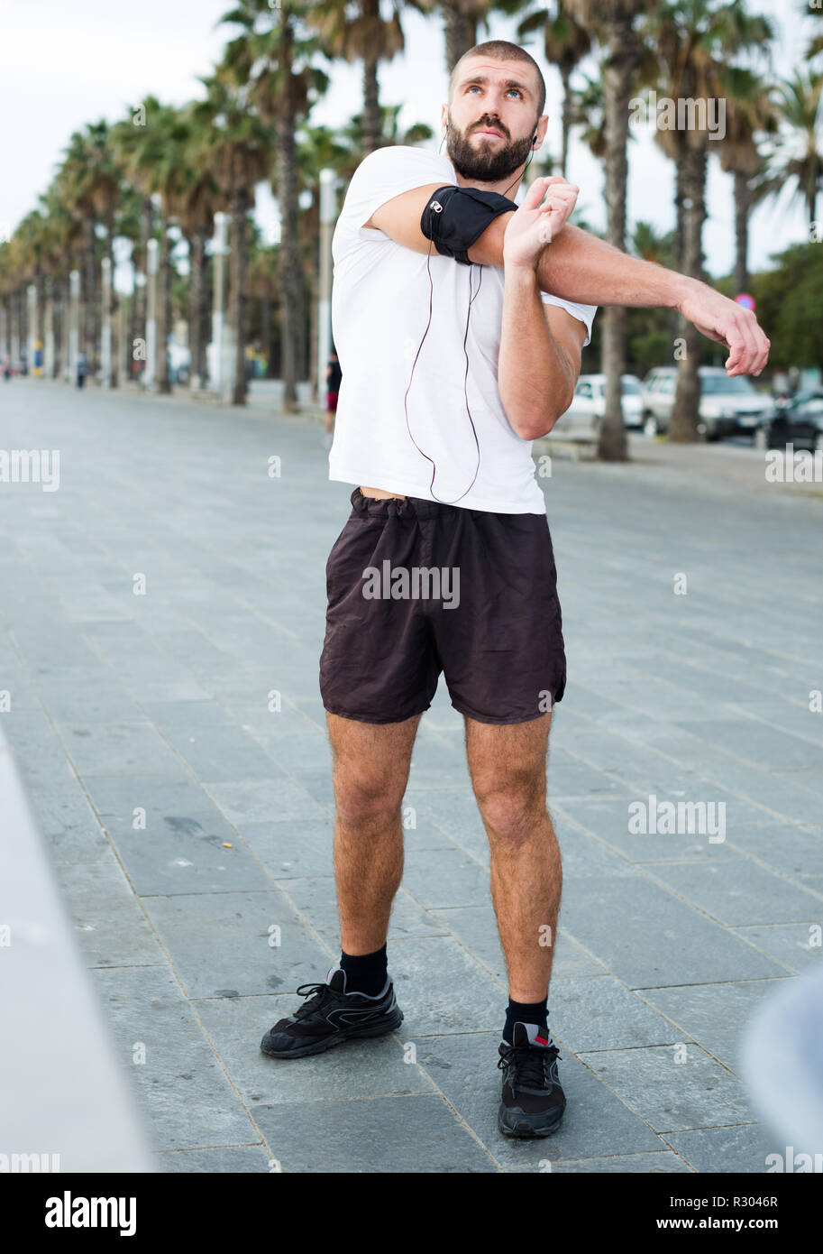 Athletic male performs warm-up exercises before training Stock Photo