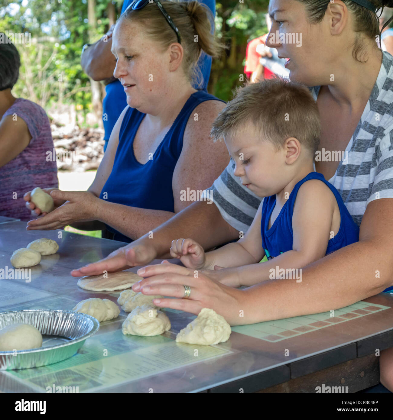 Kealakekua, Hawaii - Members of the Kona Historical Society, helped by tourists, bake bread in a Portuguese stone oven. The oven is a reproduction of  Stock Photo