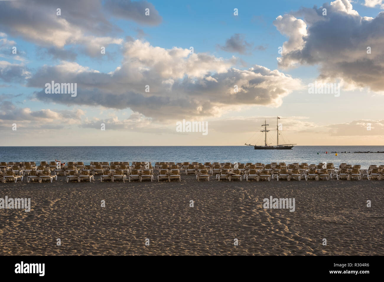 beach with sun beds and ocean background with sainling boat Stock Photo