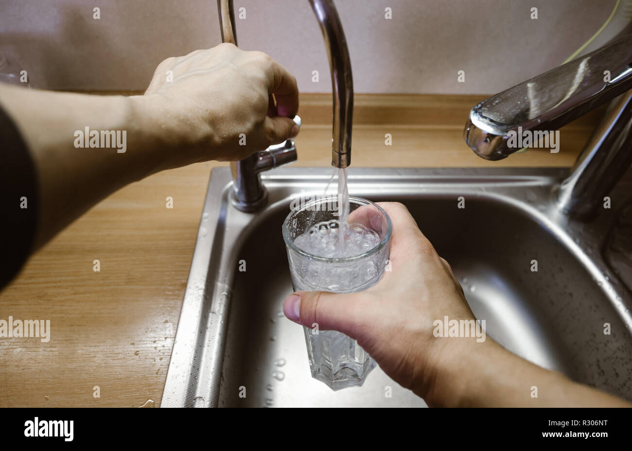 A man pours a glass of water from the tap. Wide angle first person view Stock Photo