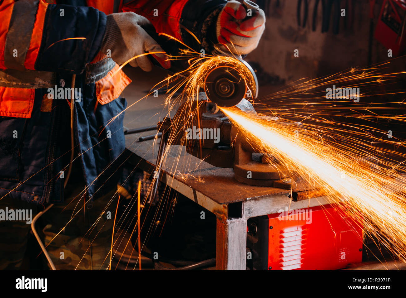 Worker cutting metal with grinder in his workshop. Sparks while grinding iron. Stock Photo