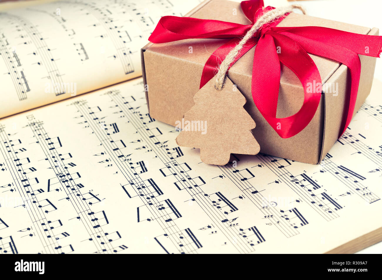 Christmas gift or present with label and twine on music sheet. Red ribbon bow. Notes. Vintage