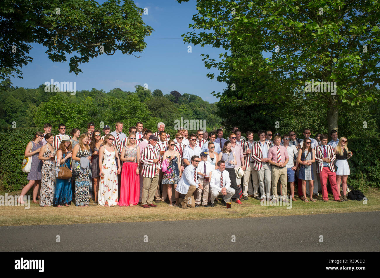 A group pose for a photograph with red, white and black striped rowing blazers at Henley Royal Regatta, Henley-on-Thames, Oxfordshire Stock Photo