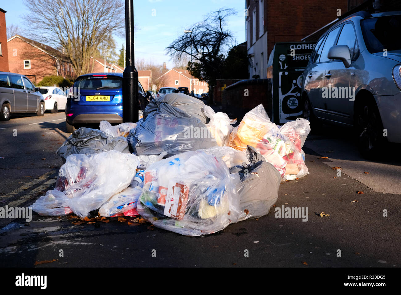 Large clear plastic bags full of domestic refuse are left lying on the pavement of a street awaiting collection by the local authority Stock Photo