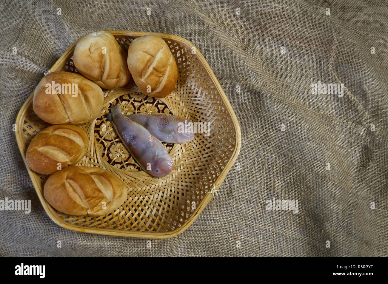 Two fish and five loaves in wicker basket Stock Photo