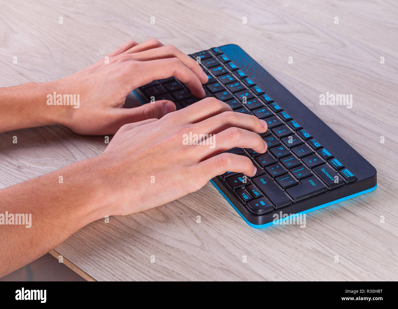 A man is typing on a wireless keyboard. Hands keyboard. Light background. Stock Photo