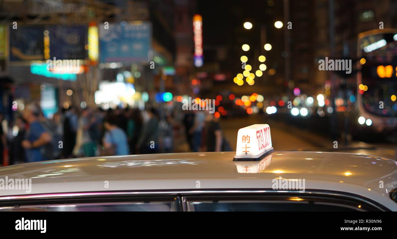 Hong Kong Taxi with lit up roof sign on busy street at night. Mong Kok, Hong Kong. Stock Photo