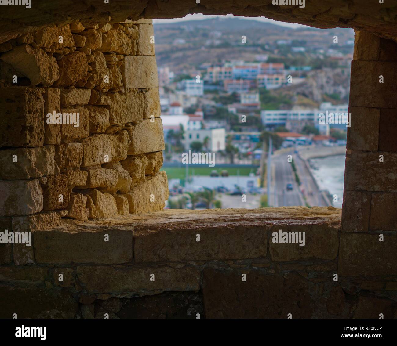 View from Venetian Fortress of Rethimno overlooking the town through a window in the stone wall. Rethimno, Crete. Stock Photo