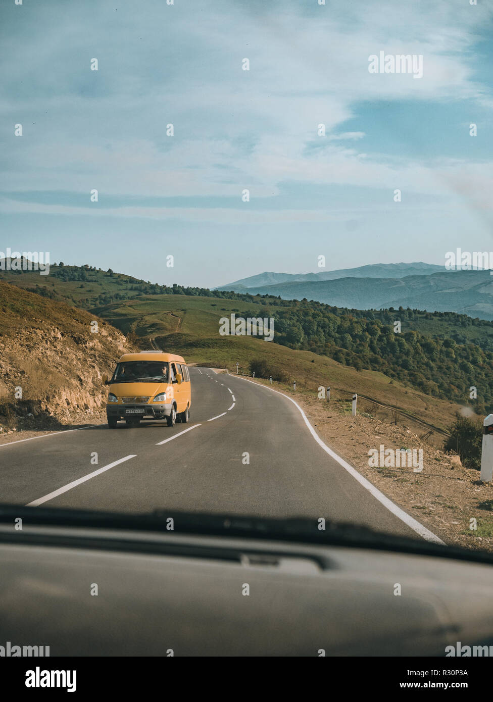 On the road in Dagestan Mountains, Russia. Wonderful view, landscape and cool yellow public bus in the front. Stock Photo