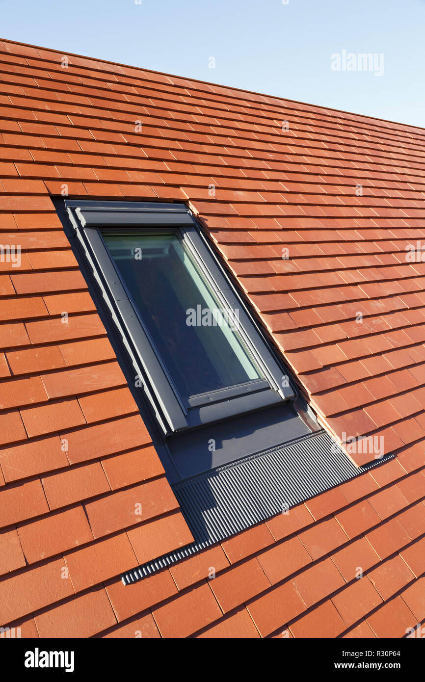 Velux style roof light window in a traditional plain clay tile house roof Stock Photo