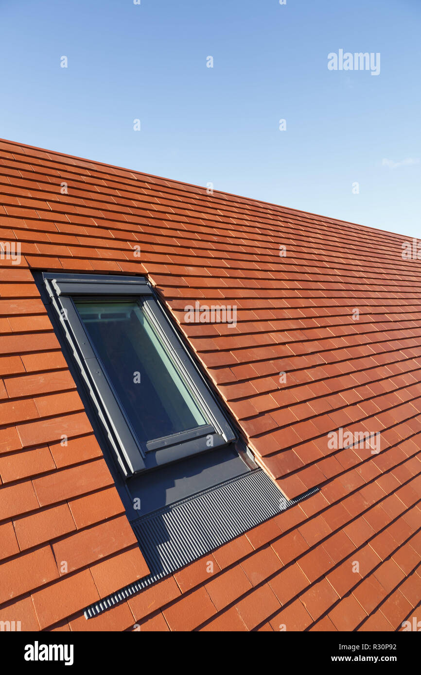 Roof light velux style window in a traditional plain clay tile house roof Stock Photo