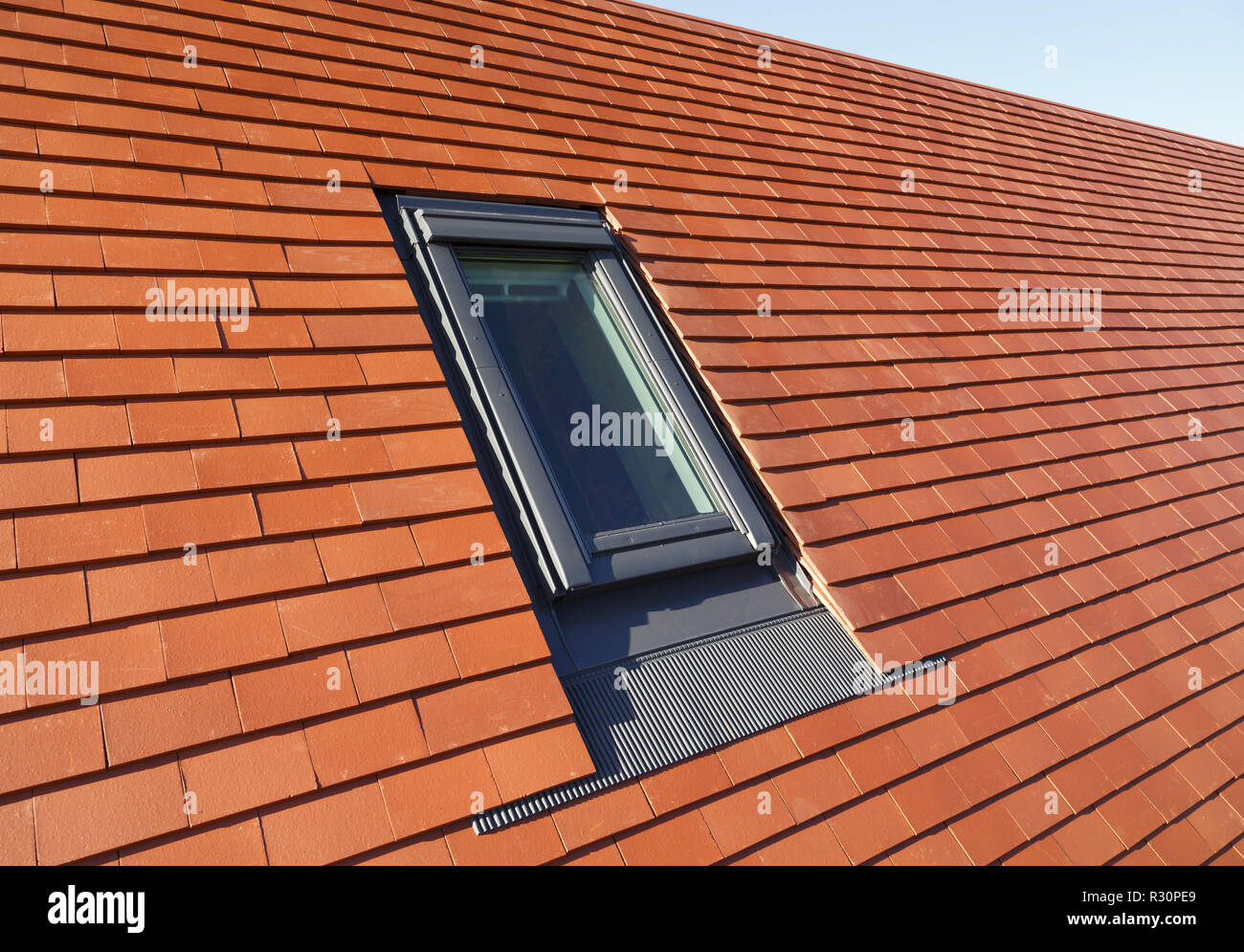 Velux type roof light window in a traditional plain clay tile house roof Stock Photo