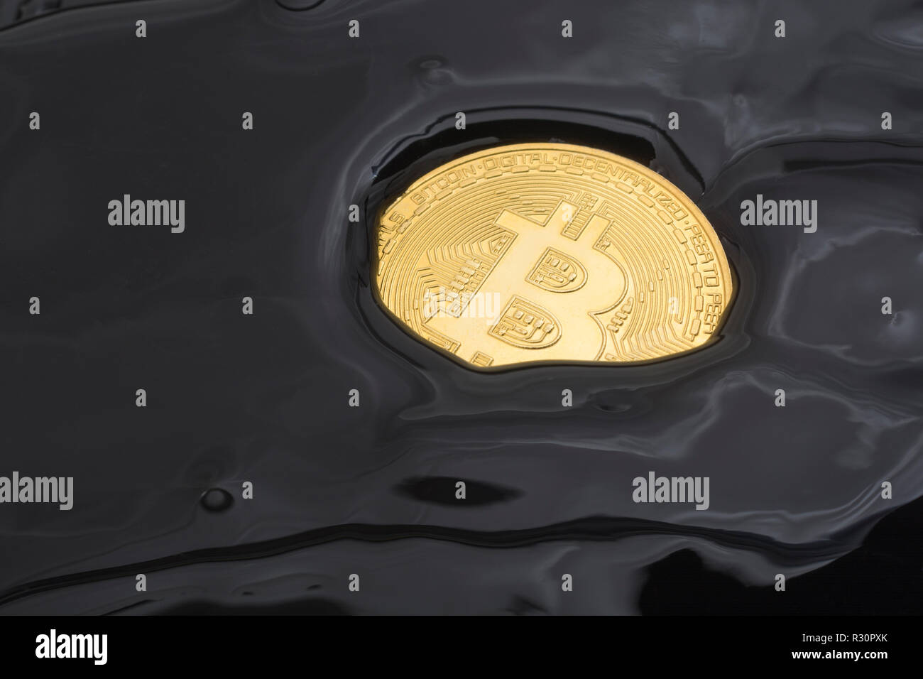 Concept picture of gold Bitcoin sinking in black morass - for 2021 Bitcoin price crash, bitcoin collapse, cryptocurrency market crash. Stock Photo