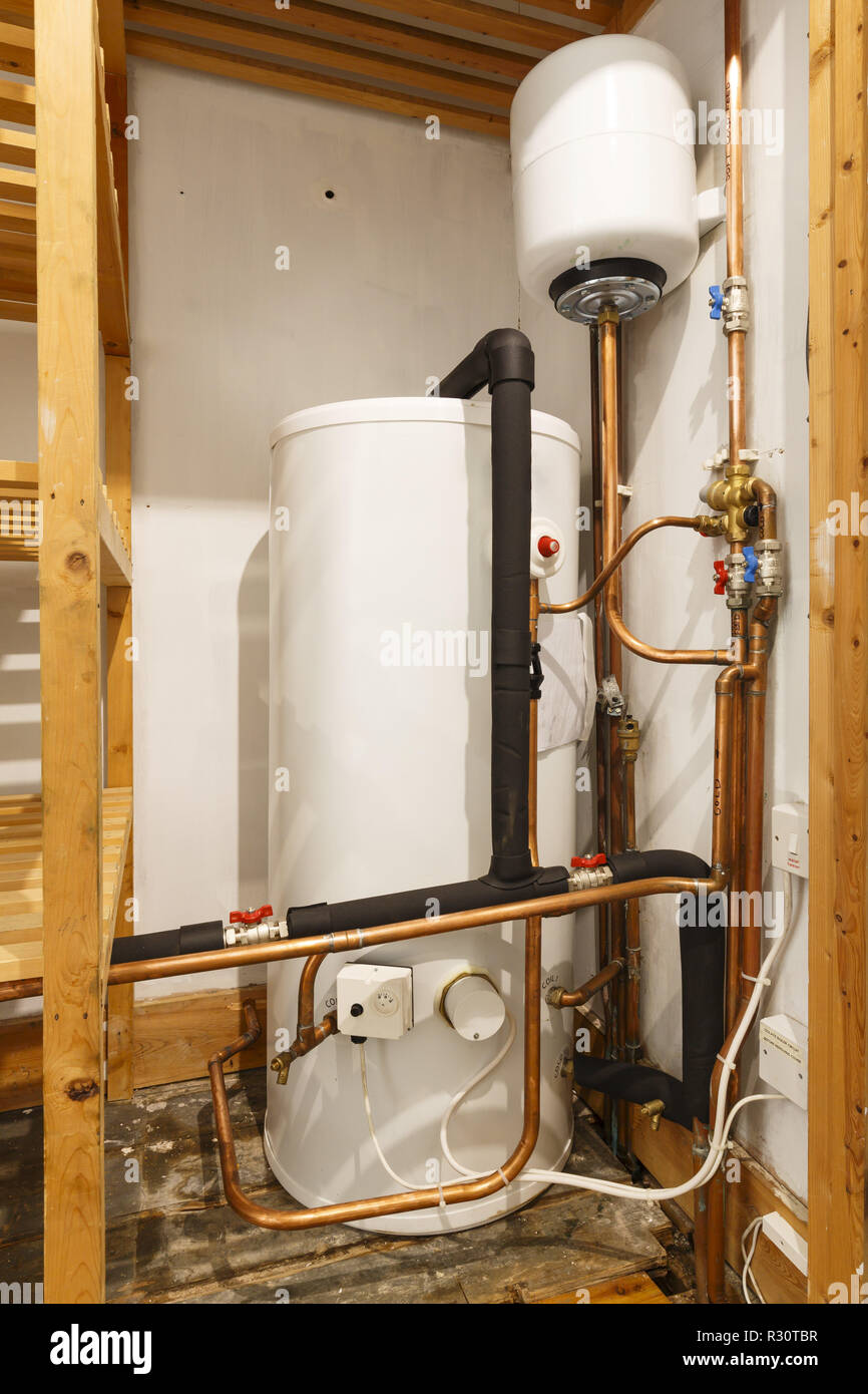 Unvented hot water cylinder and expansion vessel in an airing cupboard. UK plumbing Stock Photo