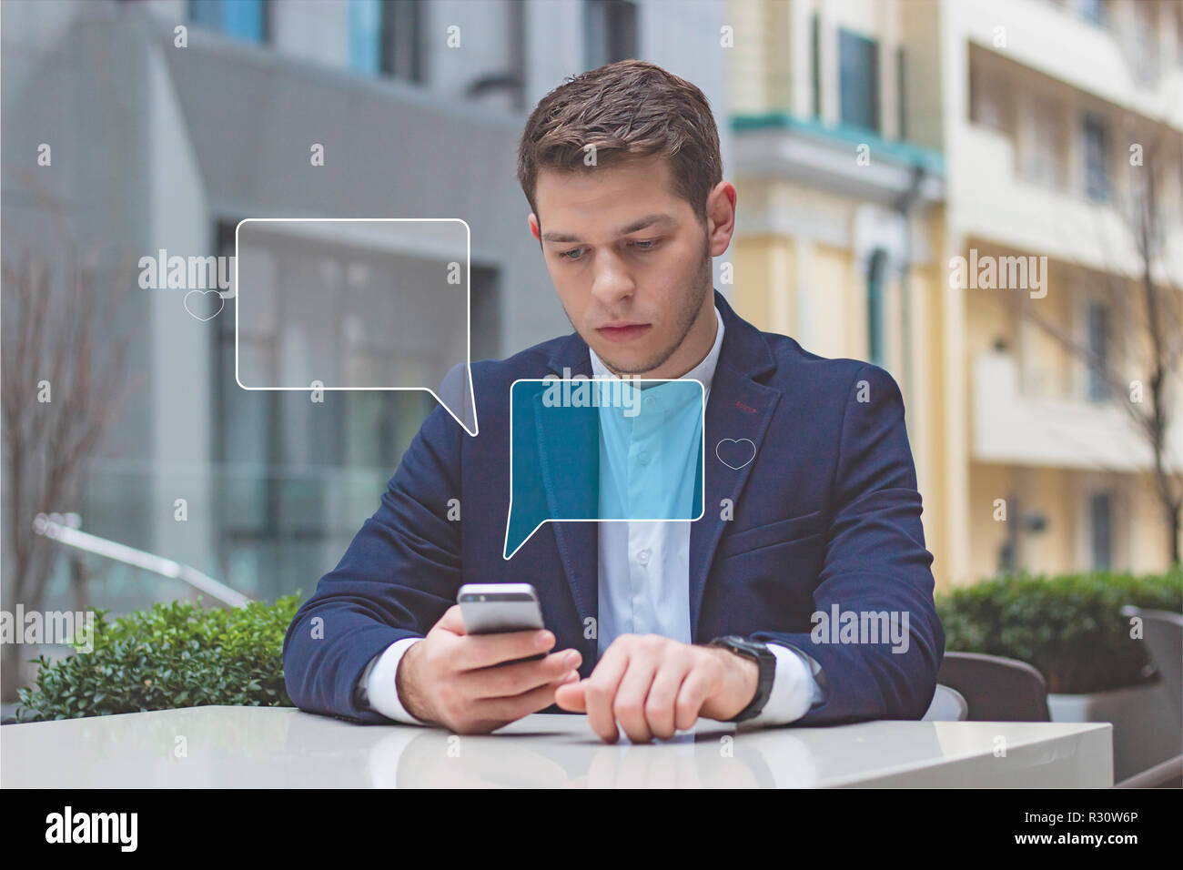 Business style. Businessman holds phone in his hand. The guy is sitting at a table on the terrace in a cafe. Stock Photo